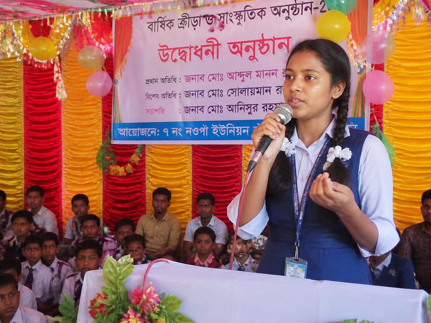 A student speaking confidently into a microphone at a school programme
